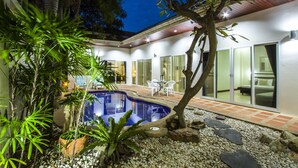 Une maison moderne dotée d’une piscine, de mobilier d’extérieur et d’un jardin bien entretenu.