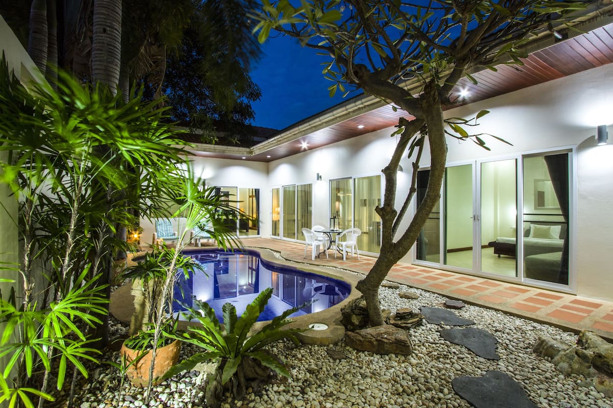 Une maison moderne dotée d’une piscine, de mobilier d’extérieur et d’un jardin bien entretenu.
