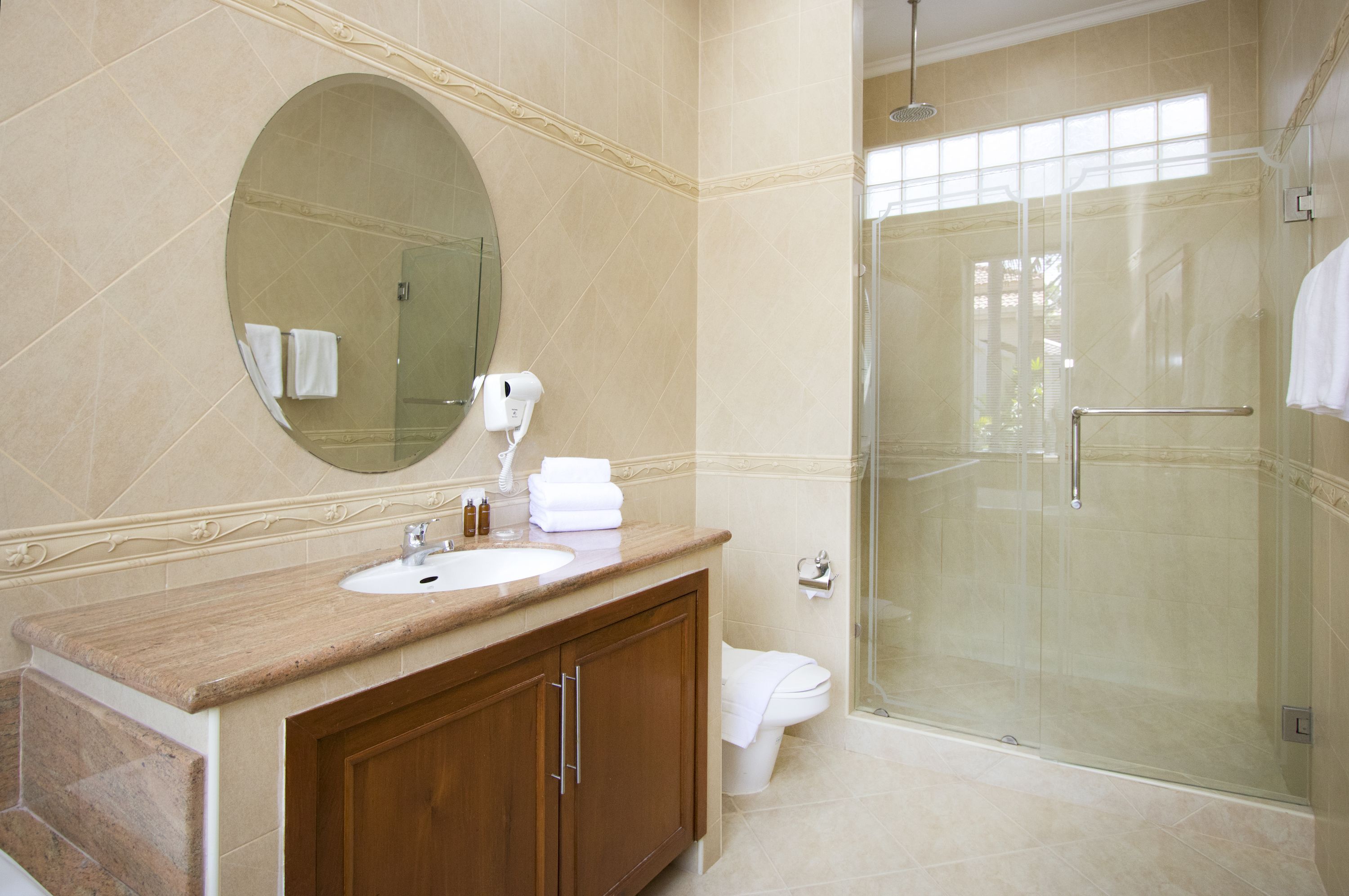A bathroom with a marble sink, a large mirror, a glass shower enclosure, and a toilet.