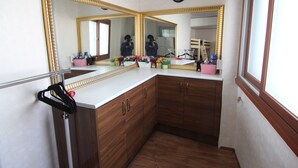 A bathroom with a large mirror, wooden cabinets, a sink, and a clock on the wall. - Empathy Guesthouse - Hostel (Daegu)