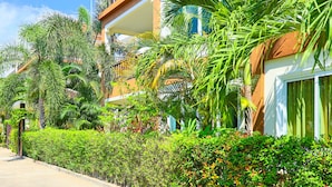 Un hôtel doté d’un balcon, d’une végétation luxuriante et surplombant un ciel bleu azur.