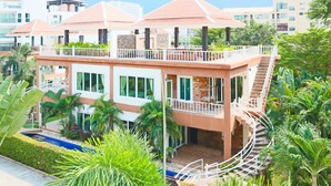Un hôtel à plusieurs étages doté d’une terrasse sur le toit, d’une piscine et d’une végétation luxuriante.