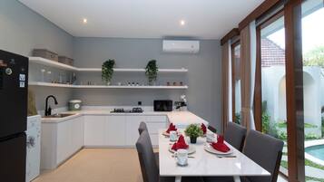 A modern kitchen with white cabinets, a dining table set for four, and a view of a swimming pool.