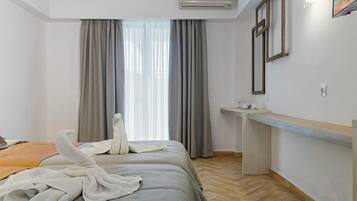 A hotel room with two beds, a desk, and a window with curtains.