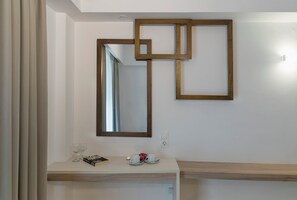A modern bathroom with a white vanity, a large mirror, and a geometric wooden frame on the wall. - Begeti Bay (Rethymno)