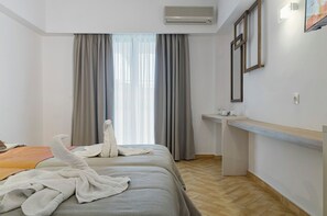 Een hotelkamer met twee bedden, een bureau en een raam met gordijnen.