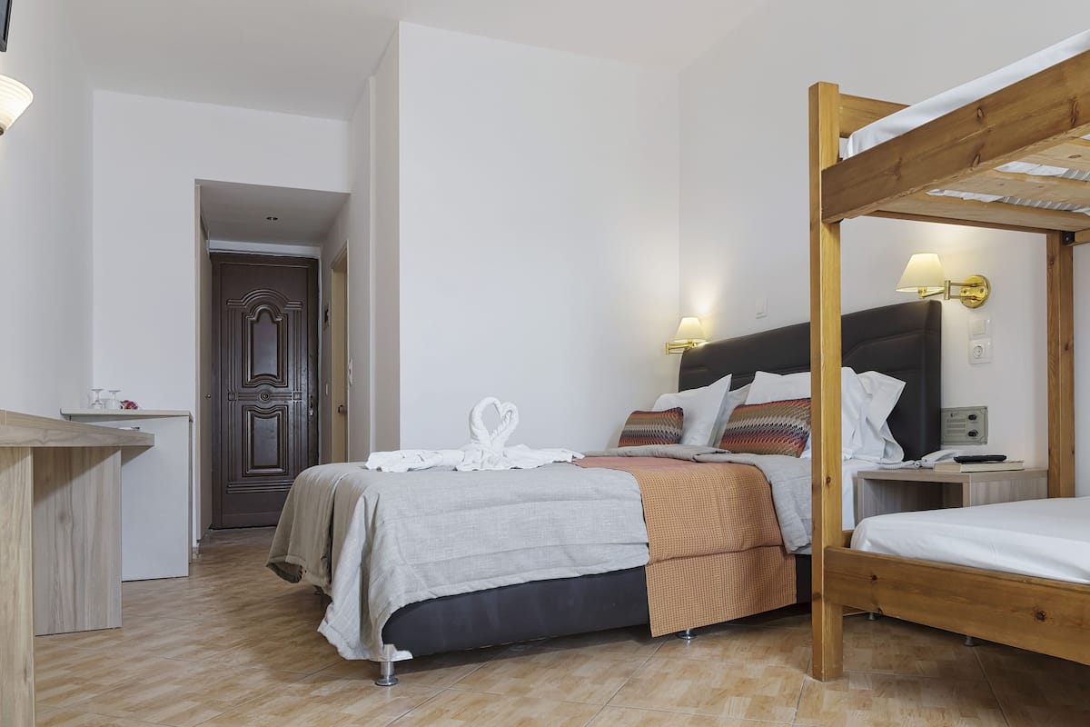 A bedroom with a wooden bunk bed, a desk, and a wardrobe.