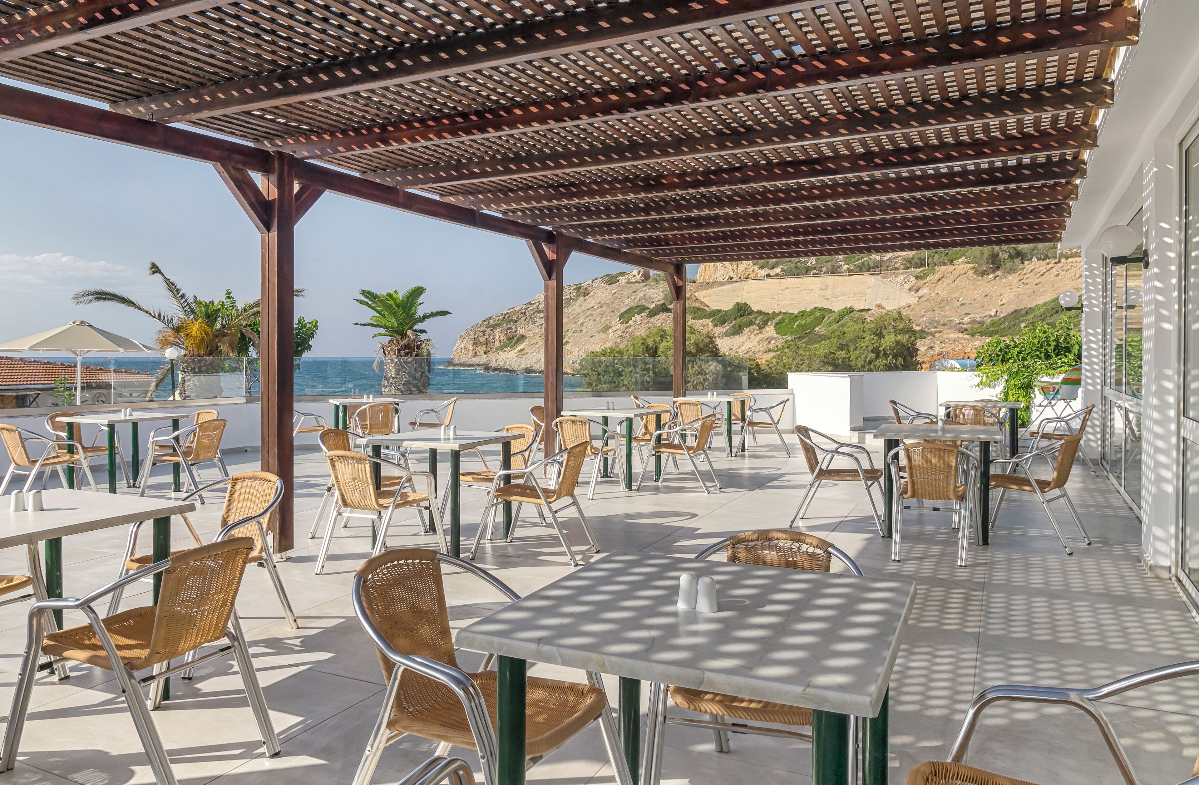 An outdoor patio area with tables and chairs, overlooking a coastal landscape.