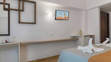 A hotel room with a bed, a desk, a television, and a mirror.