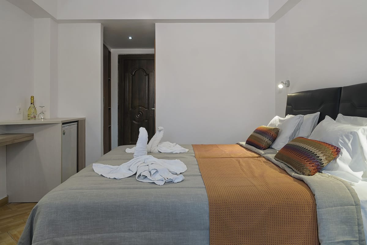 A hotel room with a bed, a desk, and a door.