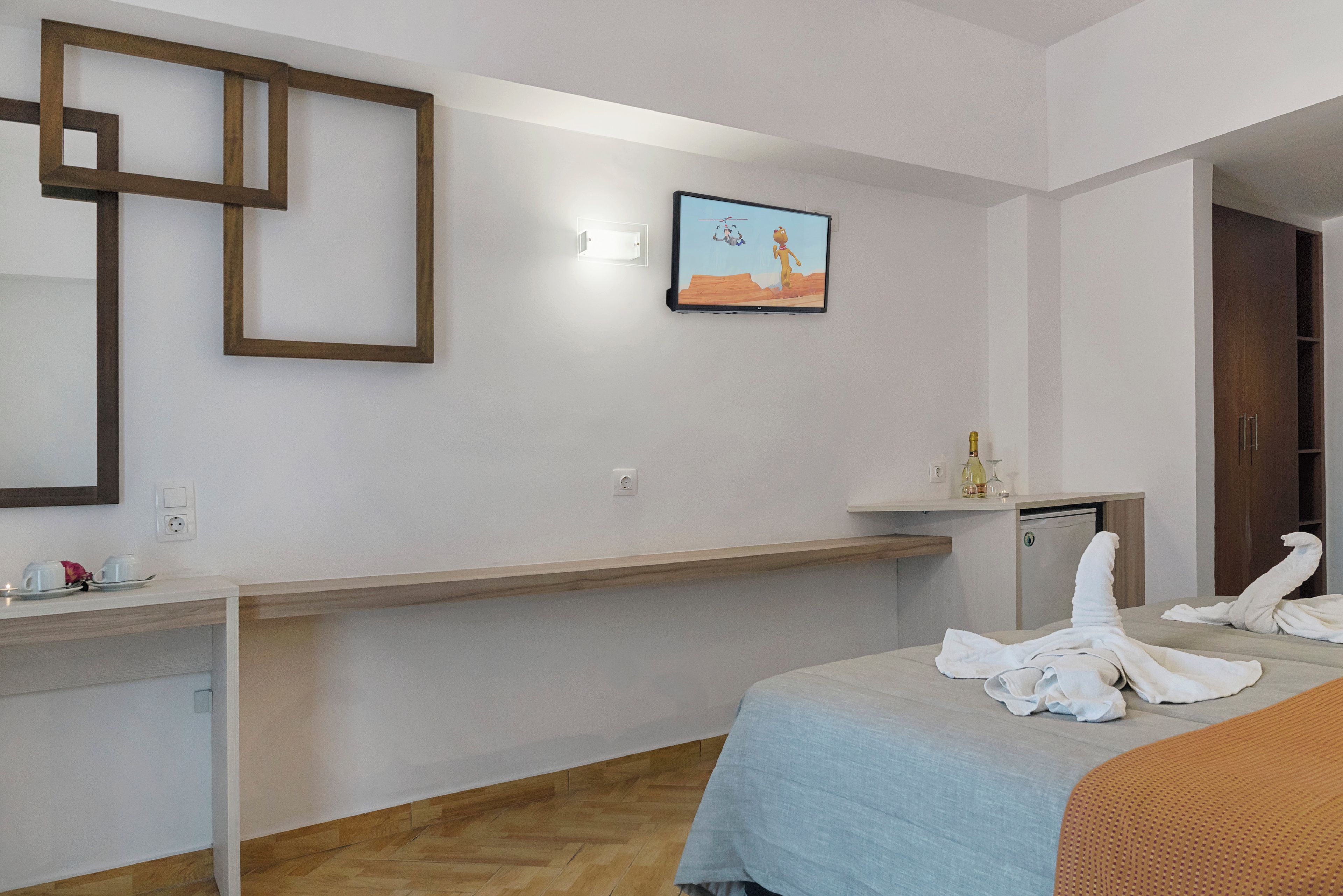 A hotel room with a bed, a desk, a television, and a mirror.