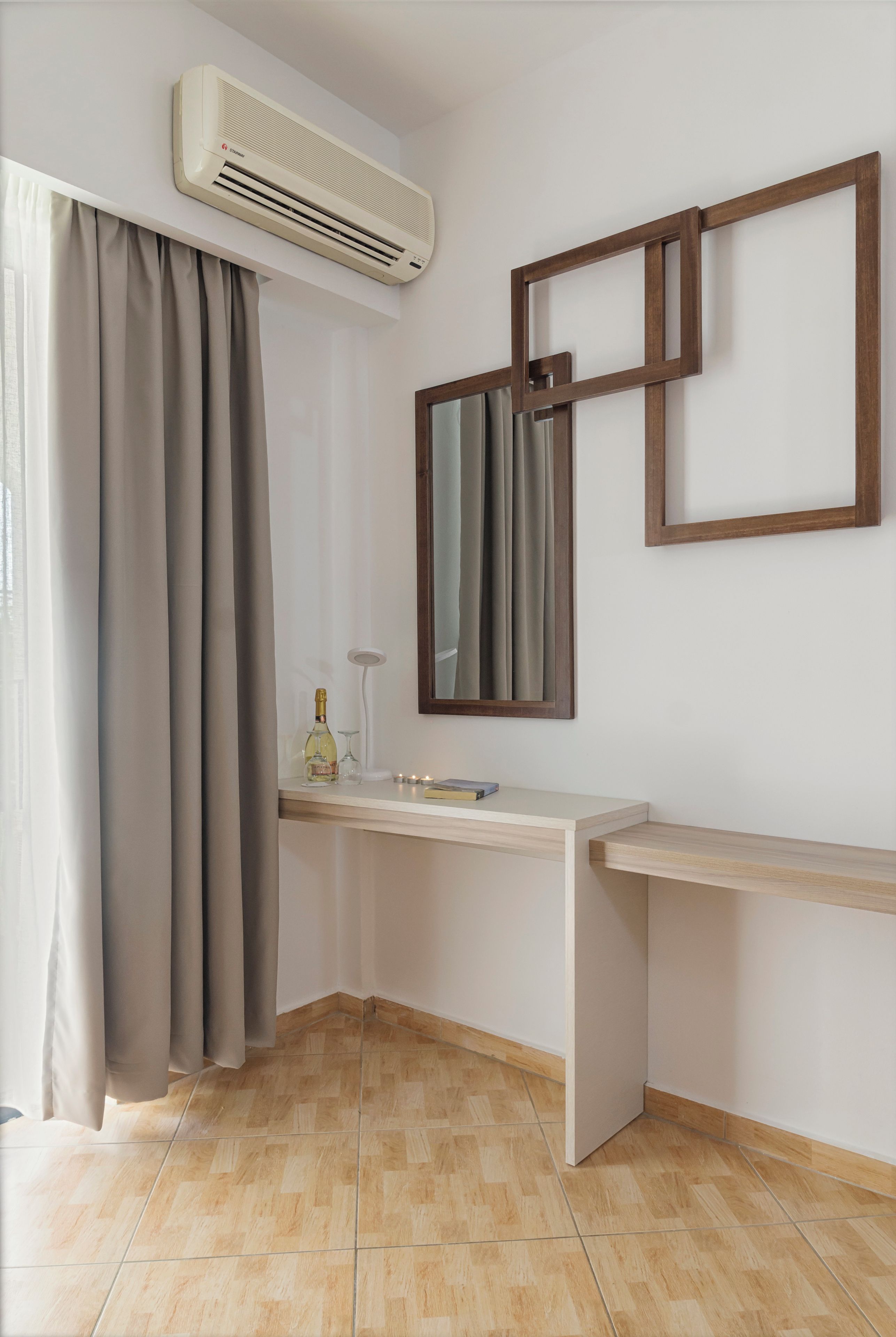 A modern bathroom with a built-in air conditioner, a vanity with a mirror, and a bottle of alcohol on the counter.