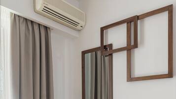 A modern bathroom with a built-in air conditioner, a vanity with a mirror, and a bottle of alcohol on the counter.