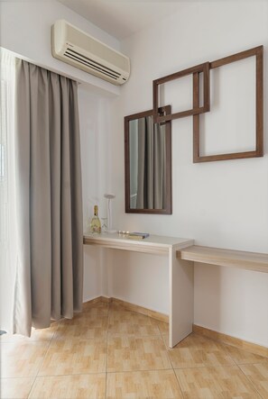 A modern bathroom with a built-in air conditioner, a vanity with a mirror, and a bottle of alcohol on the counter. - Begeti Bay (Rethymno)