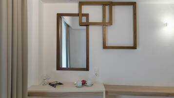 A modern bathroom with a white vanity, a large mirror, and a geometric wooden frame on the wall.