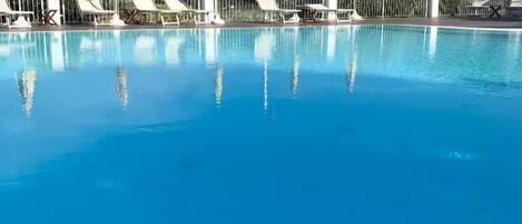 Una piscina al aire libre de temporada, sombrillas