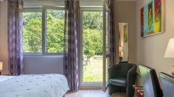 A hotel room with a bed, a chair, a desk, and a view of the outdoors.