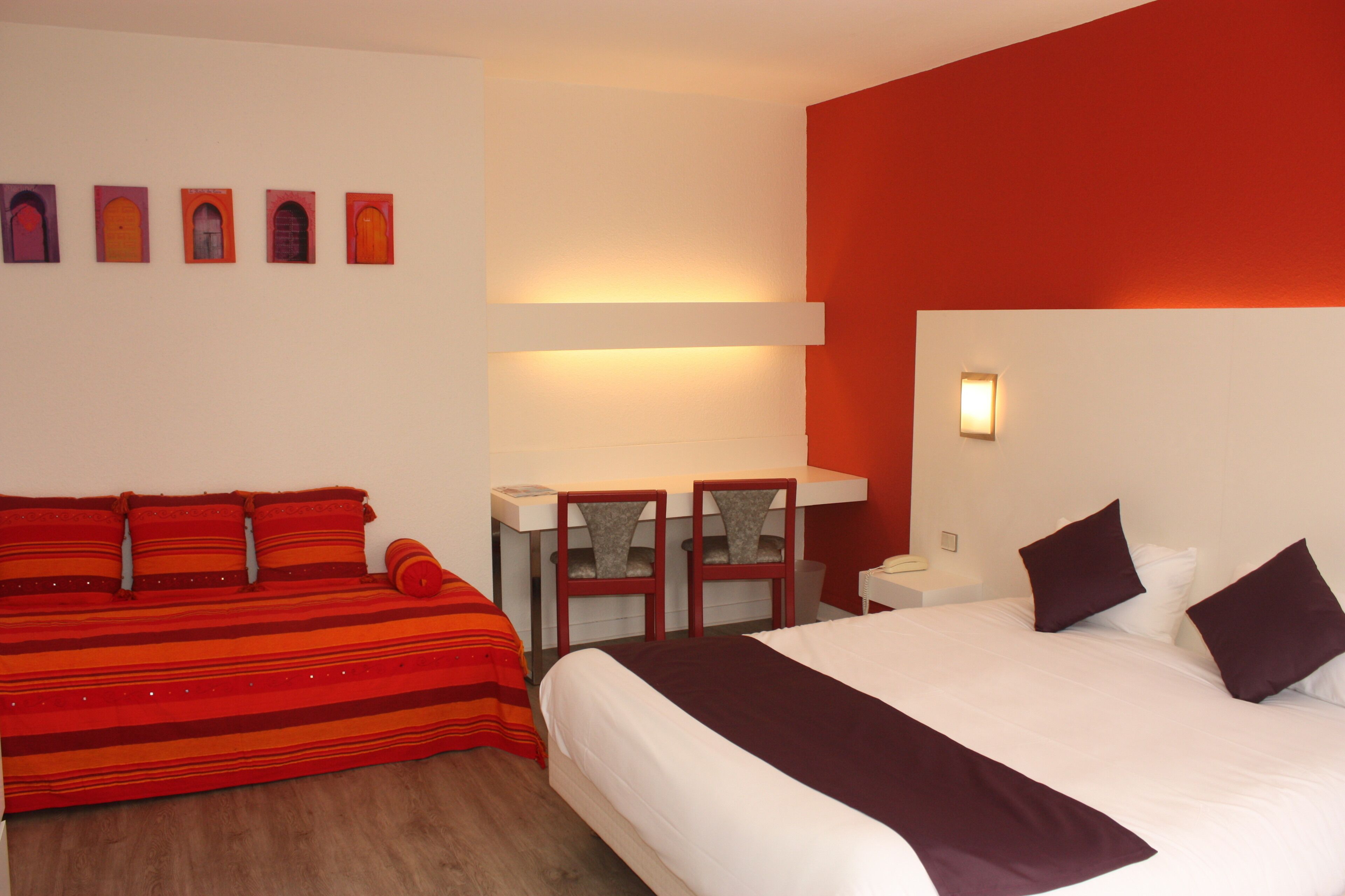 A hotel room with a bed, a sofa, a desk, and chairs.