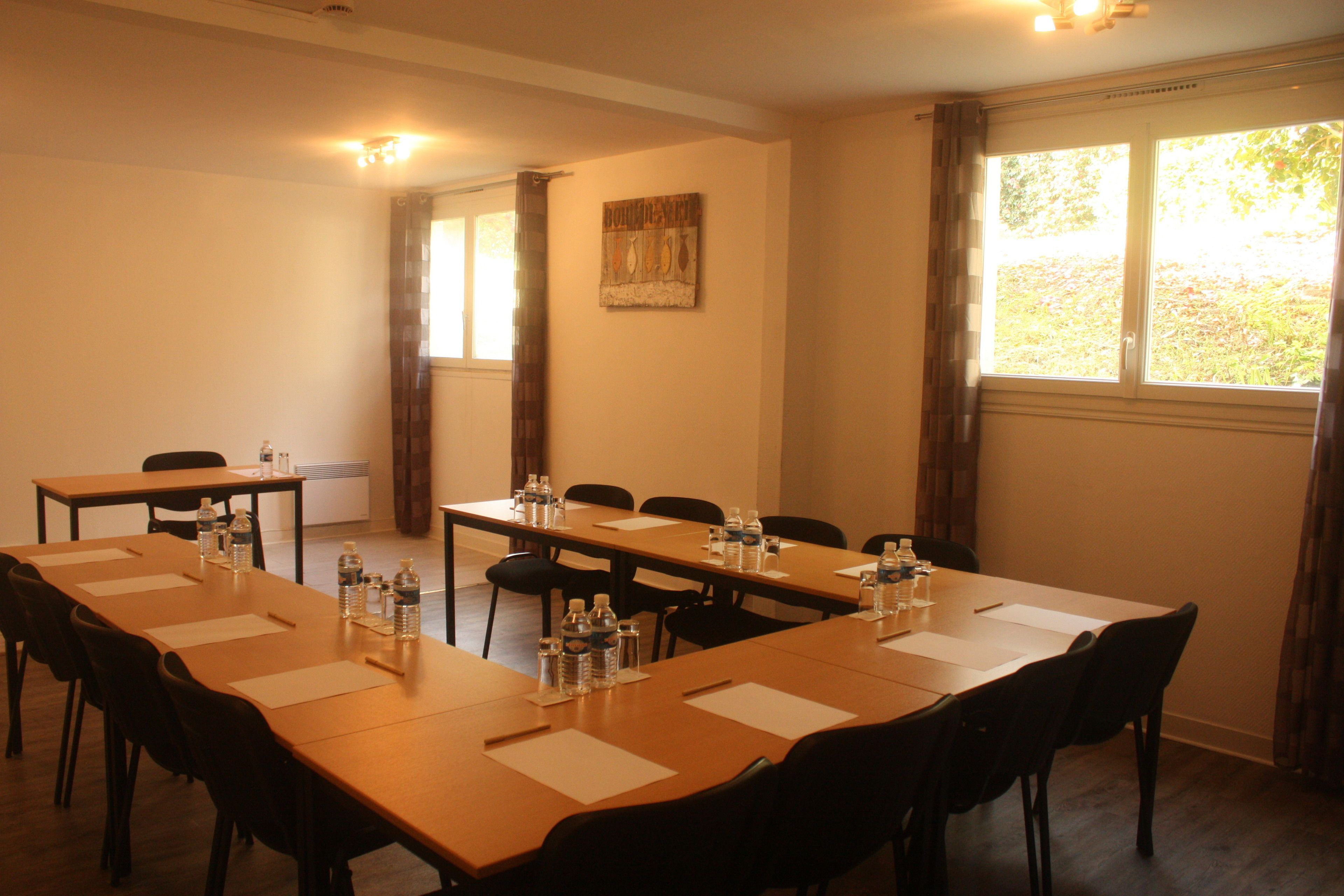 A conference room with long tables, chairs, water bottles, and papers.