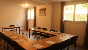 A conference room with long tables, chairs, water bottles, and papers.
