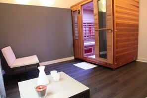 A room with a wooden cabinet, a white table with a candle, and a wicker chair. - Hotel Latitude Ouest (Locronan)