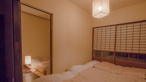 Ein Schlafzimmer mit Bett, Nachttisch, Lampe und Shoji-Bildschirm.
