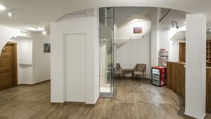 A modern interior with a curved staircase, wooden flooring, and a vending machine. - Malom Hotel és Étterem (Debrecen)