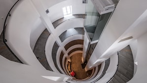 A spiral staircase with a glass railing and a wooden floor. - Malom Hotel és Étterem (Debrecen)