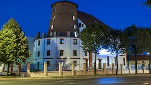 A historic building with a prominent tower and a large, multi-story structure with a white facade and brown accents. - Malom Hotel és Étterem (Debrecen)