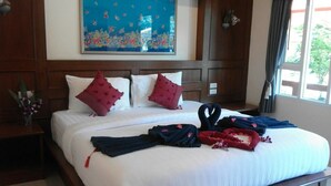 A hotel room with a large bed, two pillows, a nightstand with a vase of flowers, and a painting on the wall. - Tamarind Twin Resort (Ko Lanta)