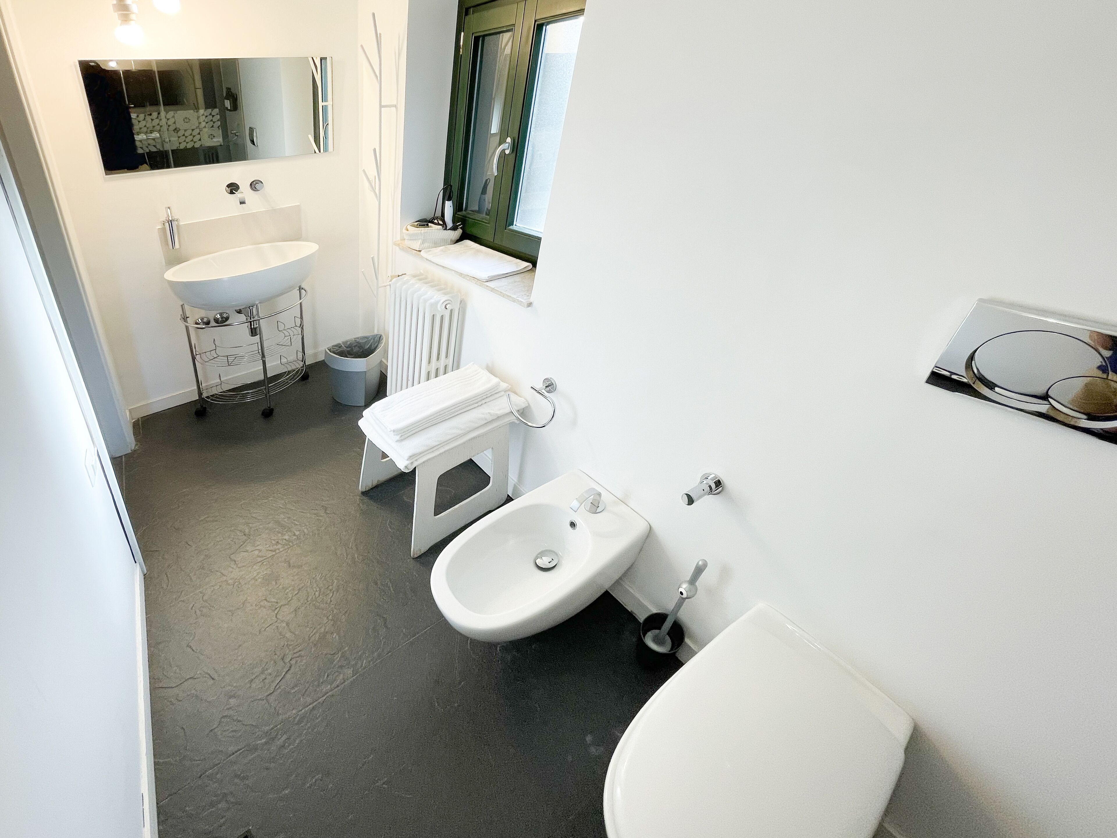 Ein modernes Badezimmer mit Waschbecken, Bidet und Toilette in Weiß.
