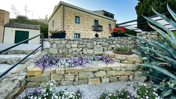 Un edificio de piedra con balcón y macetas con flores.