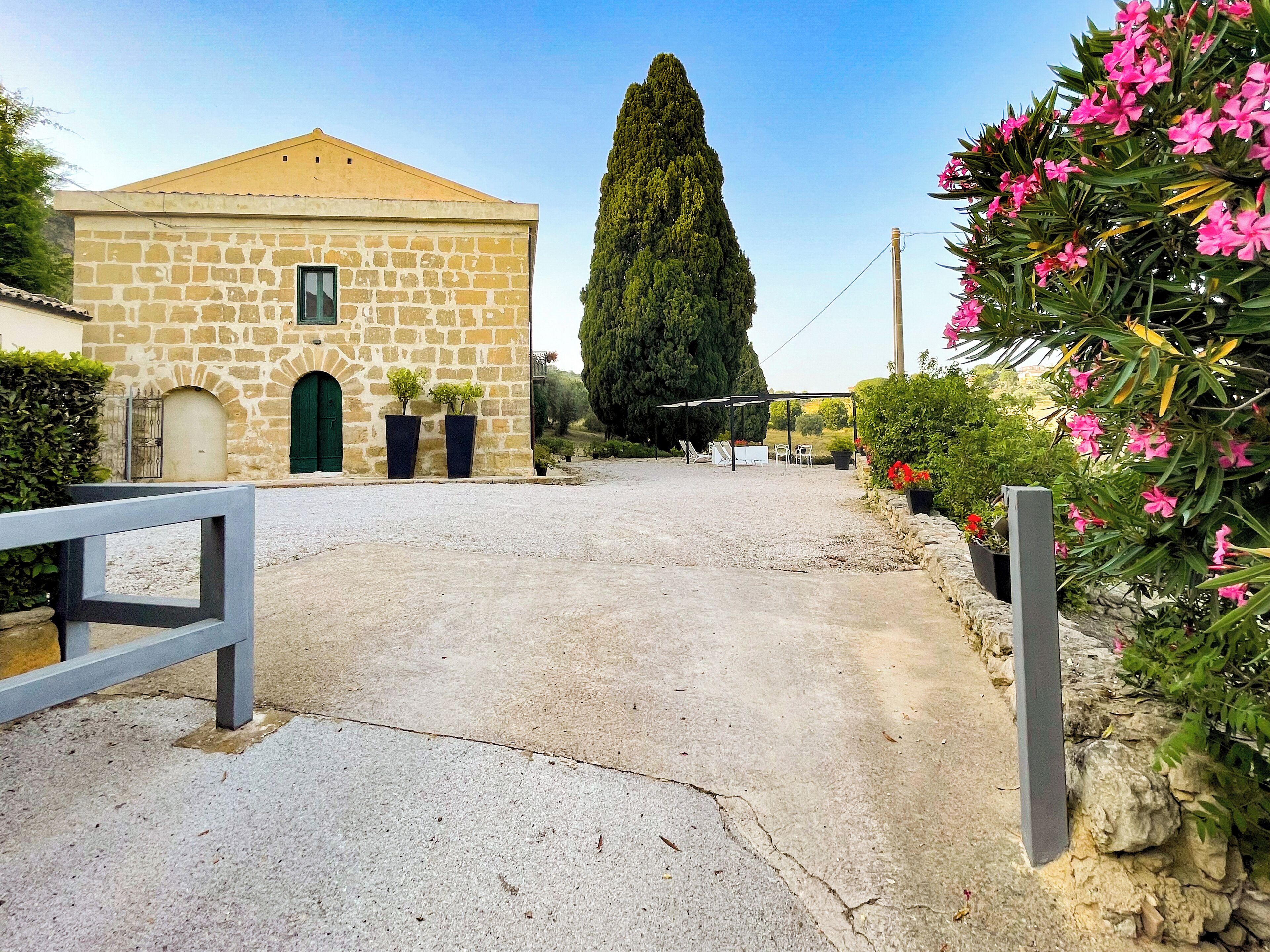 A stone building with a gravel driveway leading to a covered outdoor seating area.