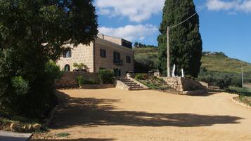 A stone building with a paved driveway and a large tree in front.