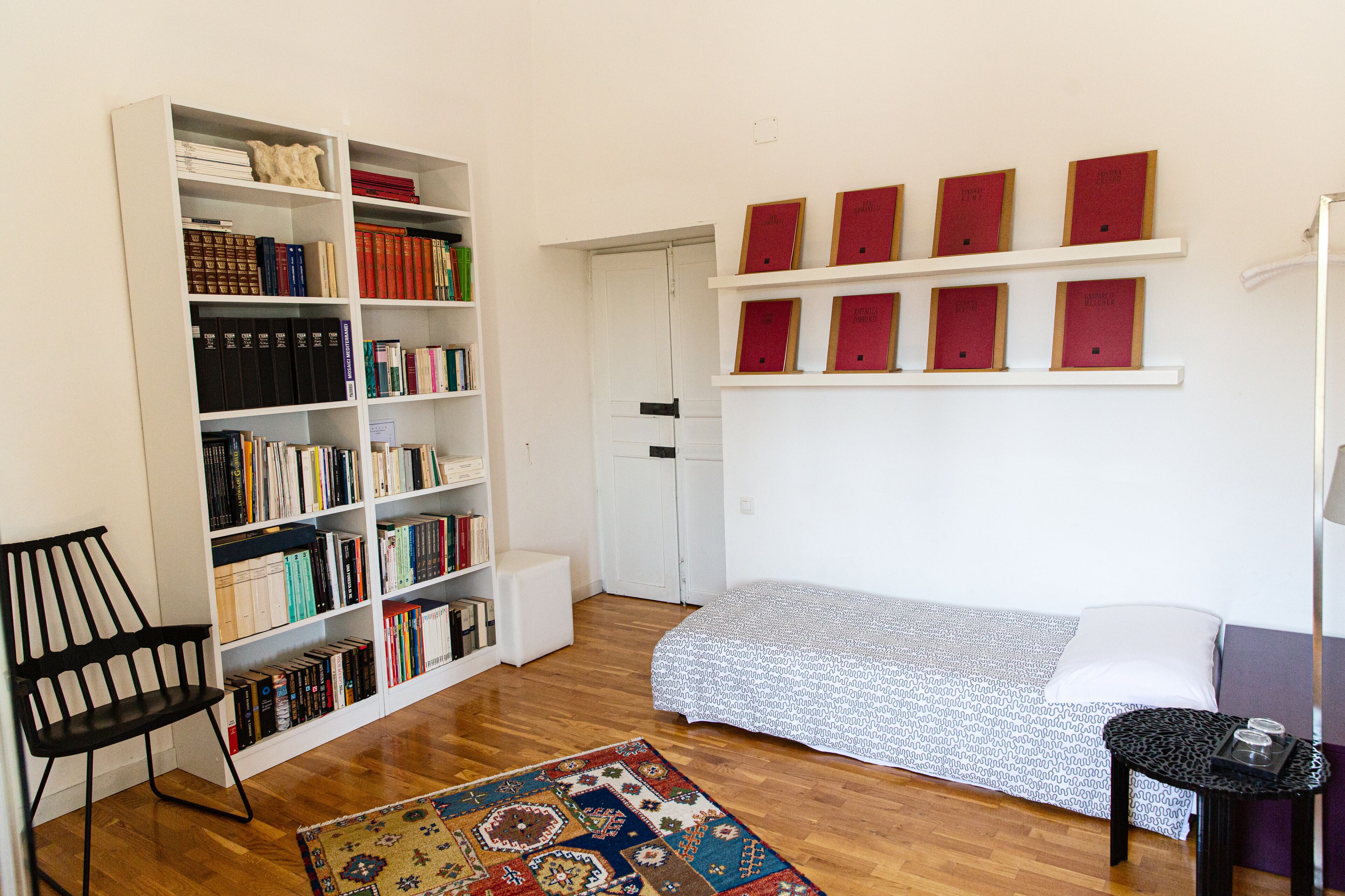 Een kamer met een bed, een boekenkast, een stoel en een vloerkleed.