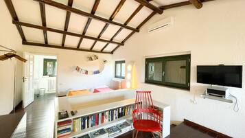Cozy living space with a high ceiling, bookshelf, and flat-screen TV.