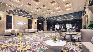 Eine geräumige Lobby mit einem gemusterten Teppich, einer Rezeption, Sitzbereichen und einer großen Kronleuchter.