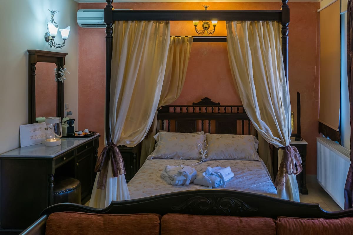 Una cama con dosel y cuatro columnas, cabecera de madera, mesita de noche con cafetera, y un cartel que dice "JUST MARRIED".