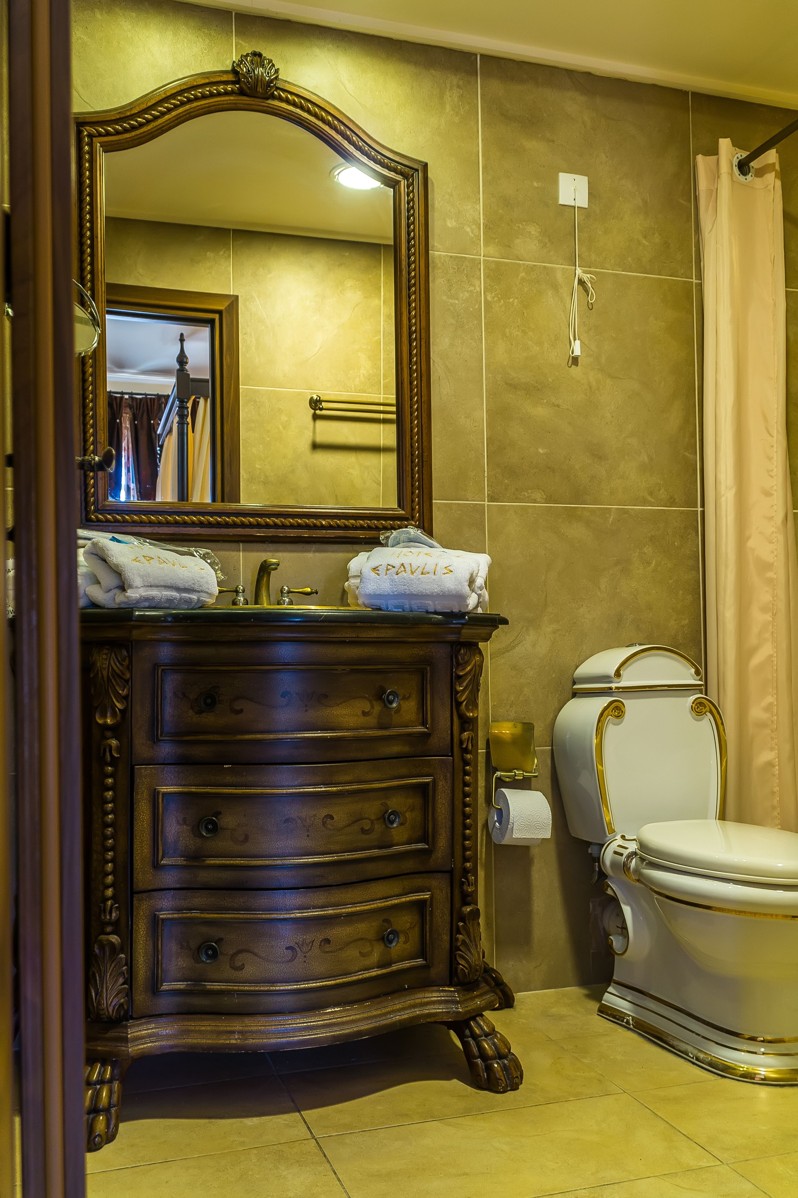 Un baño con tocador de madera, un espejo grande, inodoro y cortina de ducha.