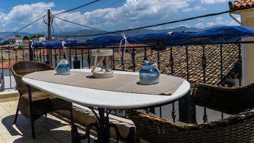 A balcony with wicker chairs, a table, and a view of the mountains.