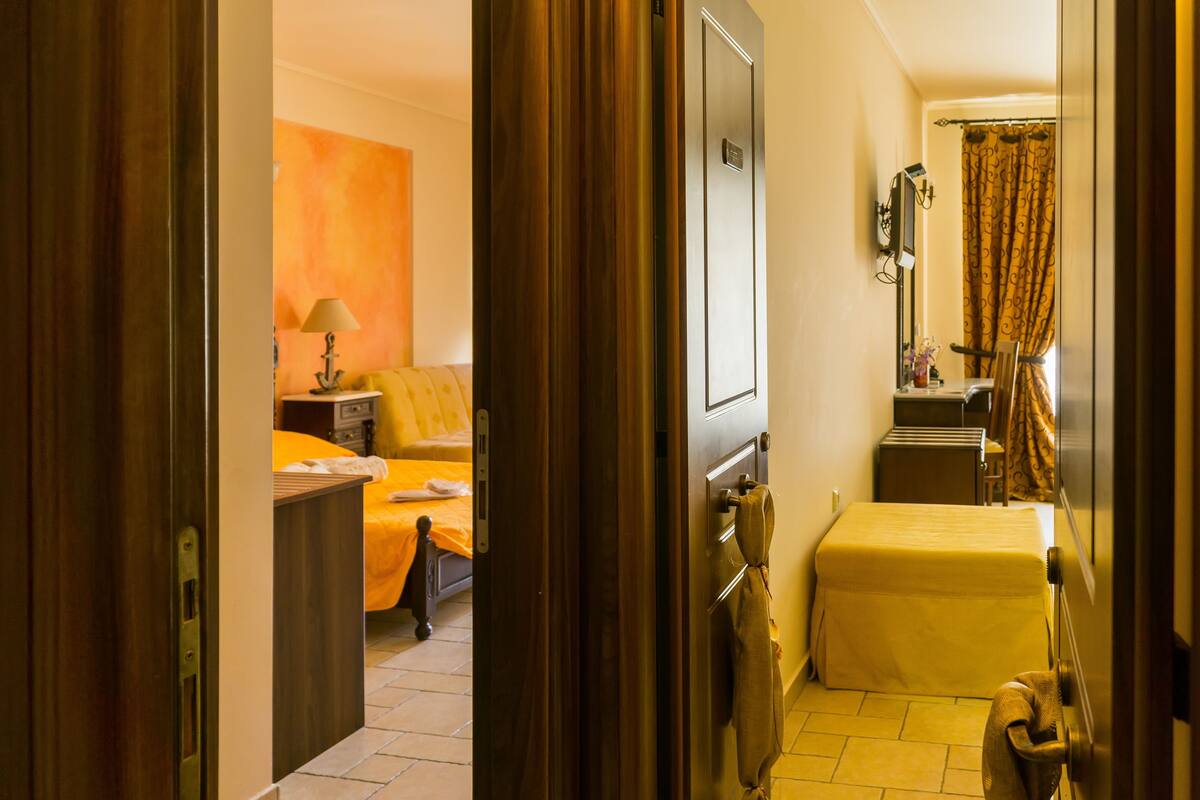 Habitación de hotel con cama, escritorio, silla, espejo y baño con cortina de ducha.