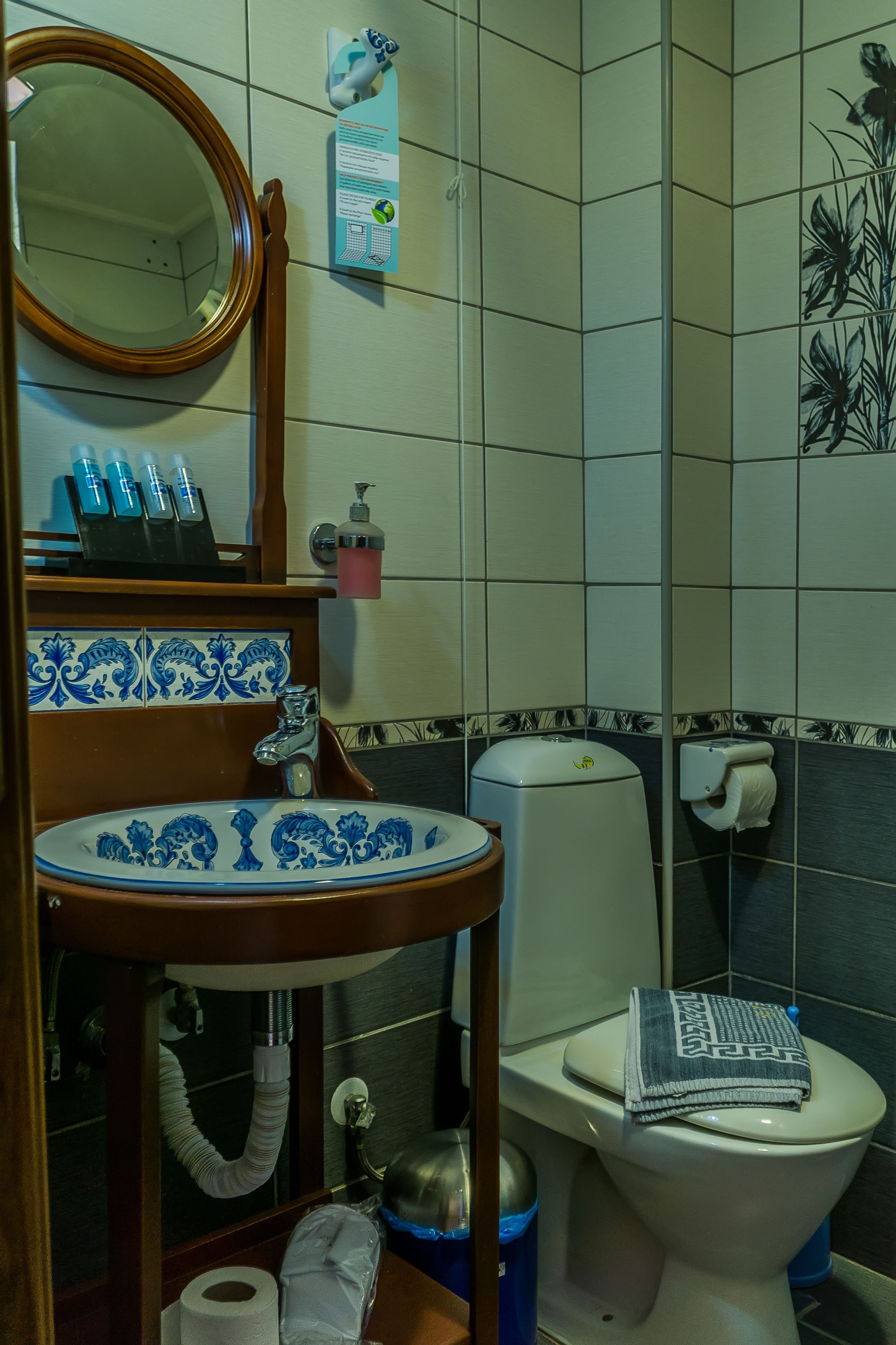 Casa de banho com lavatório, espelho, sanita e um contentor de lixo.