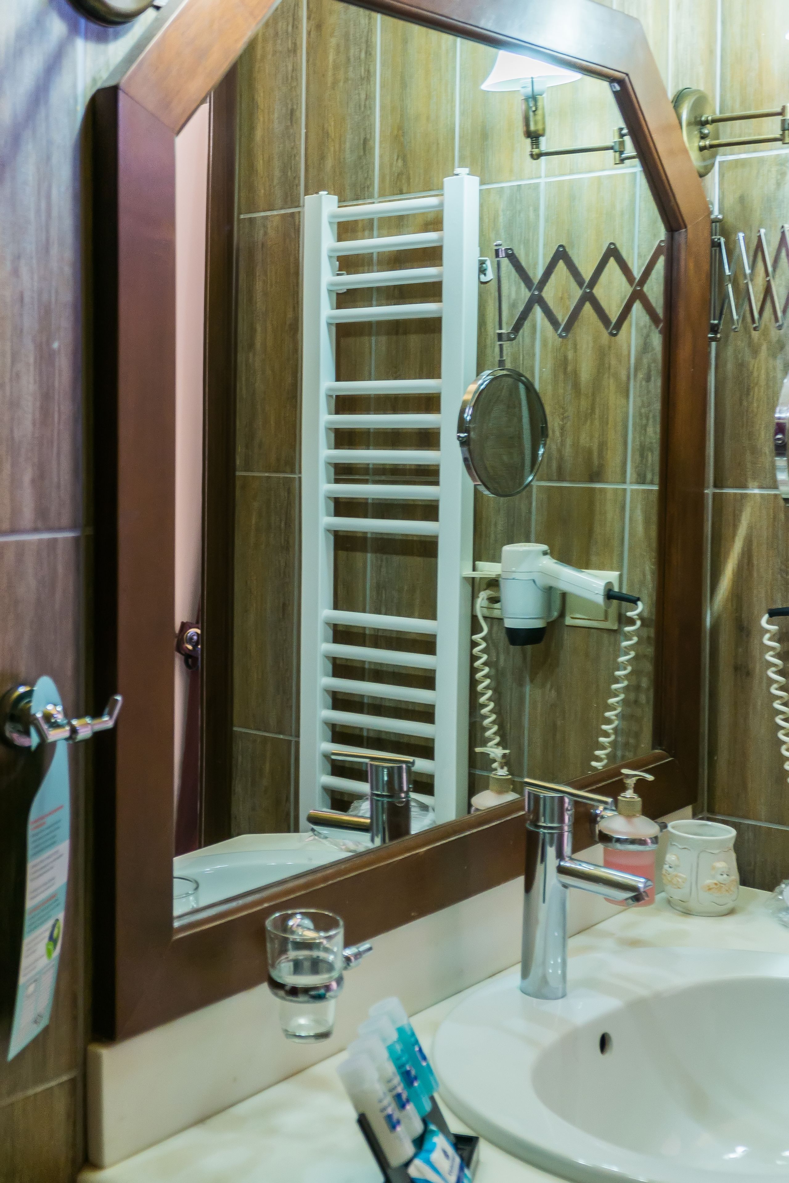 Une salle de bain avec un grand miroir, un lavabo, un porte-serviettes et un sèche-cheveux.