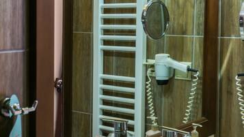 Une salle de bain avec un grand miroir, un lavabo, un porte-serviettes et un sèche-cheveux.