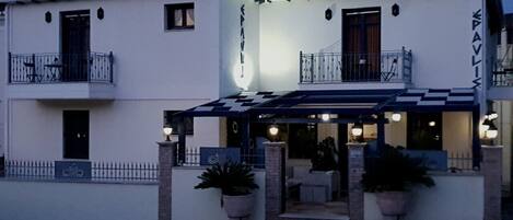 A two-story building with a balcony, a covered entrance, and potted plants.
