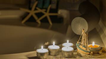 A row of lit candles on a shelf, a decorative boat candle, and a starfish in the background.