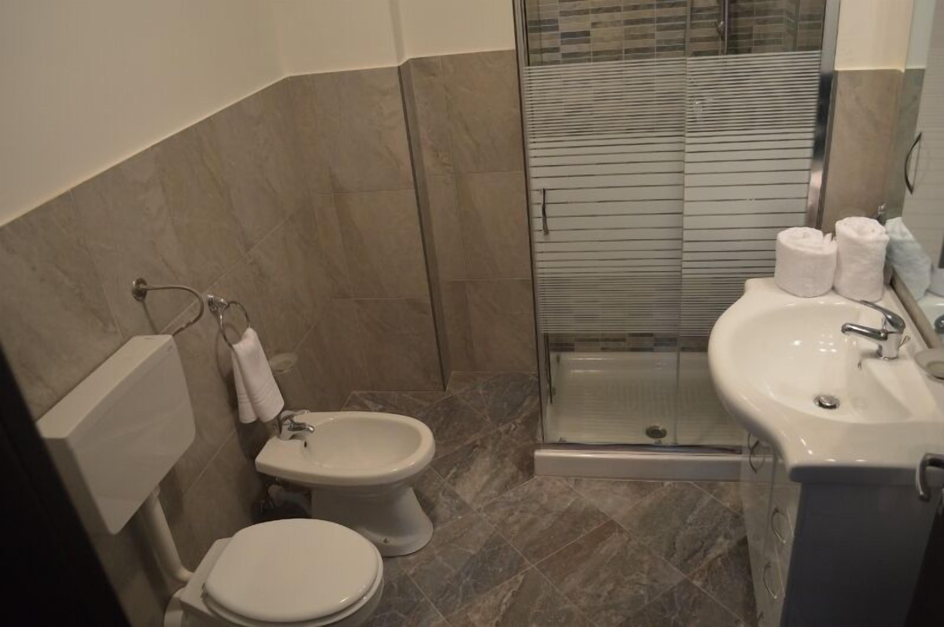 A bathroom with a toilet, bidet, and glass-enclosed shower.