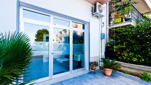Ein Hotelzugang mit Glastür, einem Balkon mit Geländer und Topfpflanzen.