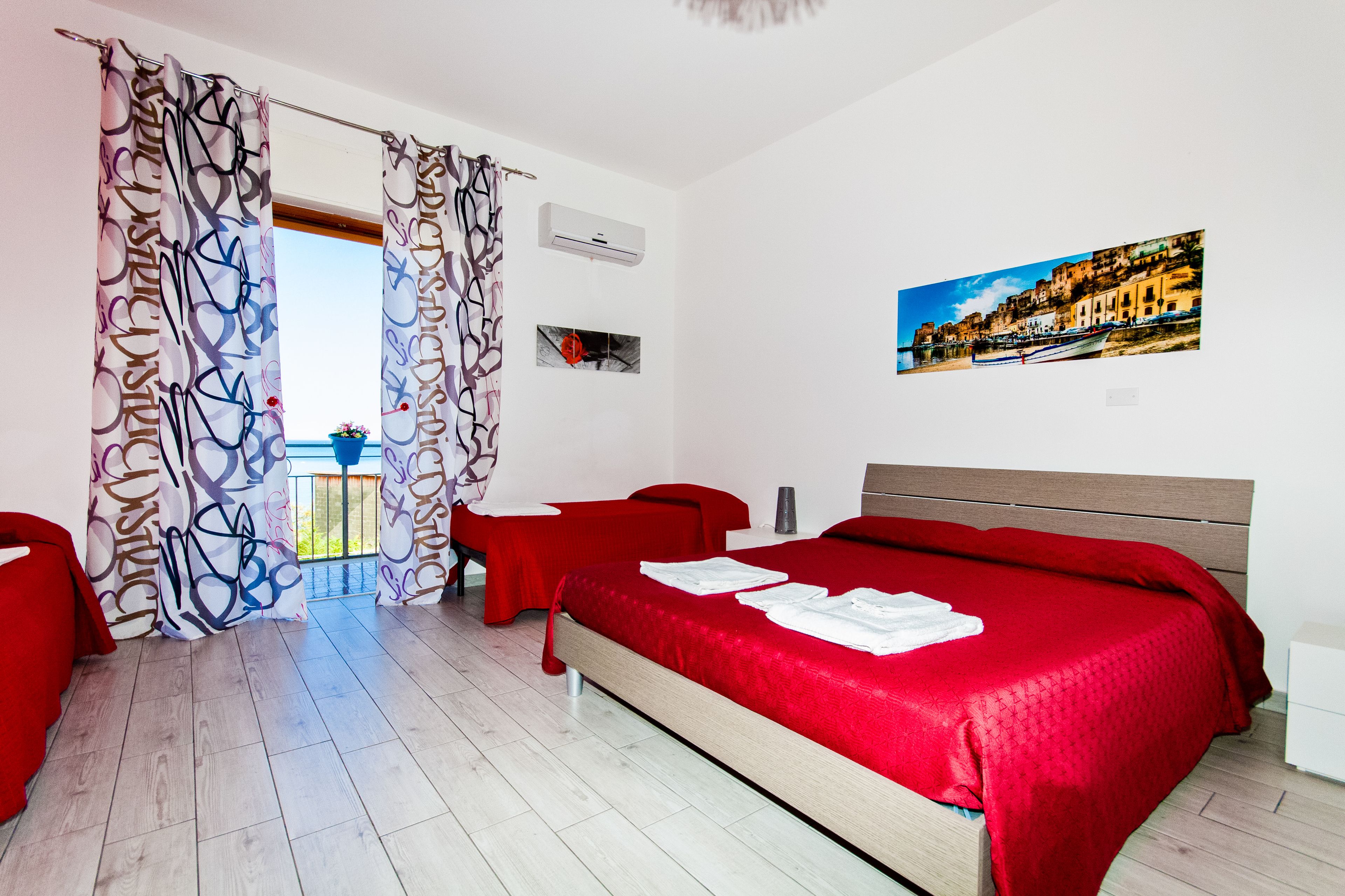 A hotel room with a bed, a desk, a chair, and a balcony with a view.