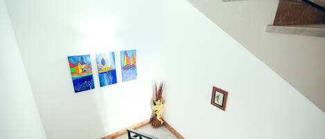 A staircase with a handrail, a wall with three framed artworks, and a small framed picture.